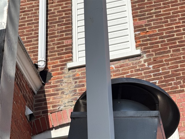 Weathered brickwork and mortar joints near an exterior window and arch.