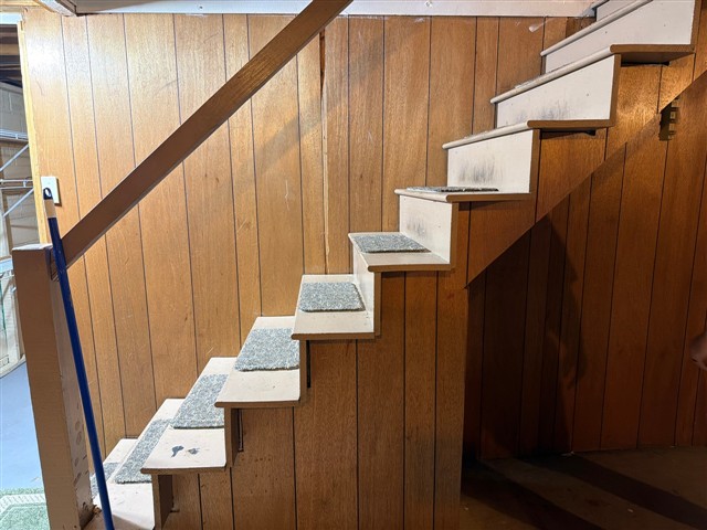 Original TMK inspection photograph of a basement staircase with a diagonal wooden handrail and an open side without a protective guardrail.